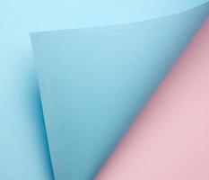 curled blue sheet of paper on pink background, abstract background photo