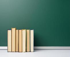 tablero escolar de tiza verde en blanco y pila de libros