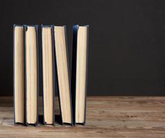 stack of various hardback books on the background of an empty black chalk board photo