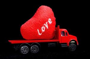 Red toy truck carrying a heart photo