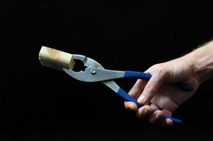 Hand holding pliers on black background photo