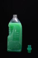 Green cleaning product bottle on black background photo