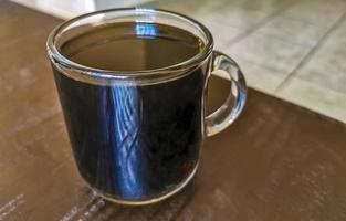 Taza de cristal de café negro de México sobre fondo de madera. foto