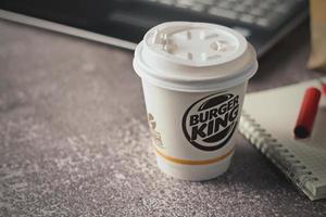 Washington, EE.UU. - 18 de enero de 2023 taza de café Burger King con portátil y portátil en una mesa gris con iluminación de estudio, Burger King es una comida popular en Estados Unidos. foto