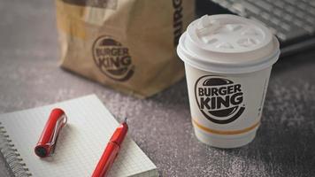 Washington, EE.UU. - 18 de enero de 2023 taza de café Burger King con portátil y portátil en una mesa gris con iluminación de estudio, Burger King es una comida popular en Estados Unidos. foto
