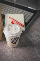 Washington, EE.UU. - 18 de enero de 2023 taza de café Burger King con portátil y portátil en una mesa gris con iluminación de estudio, Burger King es una comida popular en Estados Unidos. foto