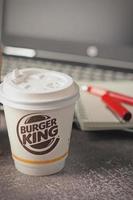 Washington, EE.UU. - 18 de enero de 2023 taza de café Burger King con portátil y portátil en una mesa gris con iluminación de estudio, Burger King es una comida popular en Estados Unidos. foto