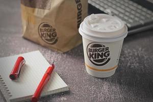 Washington, EE.UU. - 18 de enero de 2023 taza de café Burger King con portátil y portátil en una mesa gris con iluminación de estudio, Burger King es una comida popular en Estados Unidos. foto