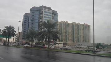 lluvia en los emiratos árabes unidos hermosa vista del lado de la carretera y sala de estar repartidor disfrutando en la lluvia bebé jugando silla hierba en la lluvia, el tráfico continúa en la carretera en un día lluvioso video