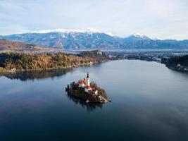 Sunrise winter scenery of magical Lake Bled. A winter tale for romantic experiences. Mountains with snow in the background. Hot air balloon flying over the lake. photo