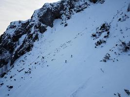 Aerial drone view of two skiers, free skiing down the mountain in the Triglav National Park. Julian Alps in Slovenia. Adrenaline sports and winter activities. Backcountry skiing or Alpine skiing. photo