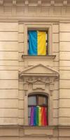 Pride of LGBT rainbow flag and flag of Ukraine in the city of Bratislava. View of the windows of the building with rainbow and blue-and-yellow flags. photo