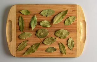 especia hoja de laurel seca aromática. especia aromática para la comida. fondo de hoja de laurel seca en una tabla de cocina de madera foto