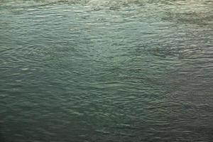 Background of the surface of the Danube river in a winter sunny day. Reflection of sun glare on the water surface with characteristic ripples. photo