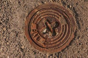 tapa de alcantarilla del sistema de gasoductos. una escotilla metálica masiva para el acceso a las comunicaciones de la ciudad en el pavimento. foto