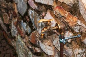 Antique brass water faucet as an architectural monument. Old tap with water on the street. photo