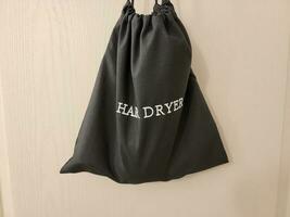 black fabric hair dryer bag hanging on wall photo