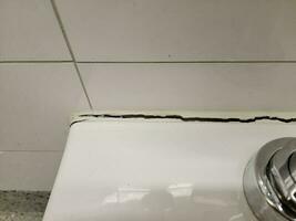 toilet in bathroom with crack in the wall or caulk photo