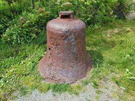 old rusted iron bell on green grass or lawn photo