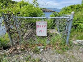 keep off sign on metal fence near water near sea photo