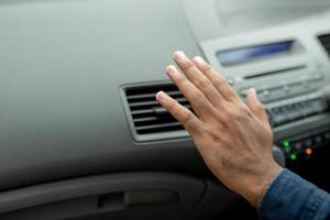 primer plano de un conductor de mano comprobando el aire de ajuste del acondicionamiento del sistema de refrigeración con flujo de aire frío en el coche. dejar espacio para escribir texto. foto