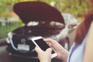 close up female hand using a mobile smart phone call a car mechanic ask for help assistance because car broken on the roadside. blank of empty screen. photo