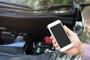 close up young business man hand using a mobile smart phone call a car mechanic ask for help assistance because car broken on the roadside. blank if empty screen. photo