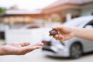 Car key, man handing over gives the car key to the other male on car an home background. Leave space to write a description of the message text. photo