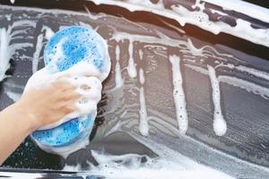 trabajador de personas hombre sosteniendo la mano esponja azul y ventana limpiadora de espuma de burbujas para lavar el coche. concepto de lavado de autos limpio. dejar espacio para escribir mensajes. foto