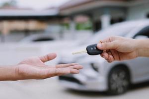 la llave del auto, el hombre que entrega le da la llave del auto al otro hombre en el auto como fondo de casa. deje espacio para escribir una descripción del texto del mensaje. foto