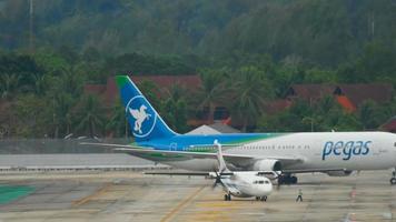 PHUKET, THAILAND DECEMBER 2, 2016 - Bangkok airways ATR 72 towing and IKAR Boeing 767 in Pegas livery taxiing after landing. Rainy weather video