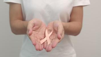 Frauenhand, die Pfirsichband für den Monat des Bewusstseins für Gebärmutterkrebs im September hält. konzept des gesundheitswesens und des weltkrebstages video