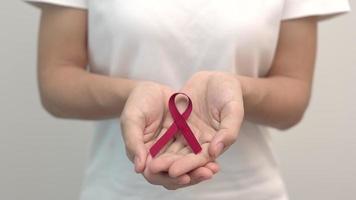 Hand holding Red Ribbon for December World Aids Day, multiple myeloma Cancer Awareness month and National Red ribbon week. Healthcare and world cancer day concept video