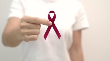 mano sosteniendo la cinta roja para el día mundial del sida de diciembre, el mes de concientización sobre el cáncer de mieloma múltiple y la semana nacional de la cinta roja. concepto de salud y día mundial del cáncer video