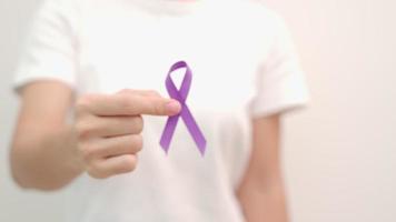 Hand holding purple Ribbon for Pancreatic, Esophageal, Testicular cancer, world Alzheimer, epilepsy, lupus, Sarcoidosis, Fibromyalgia and domestic violence Awareness month. World cancer day concept video