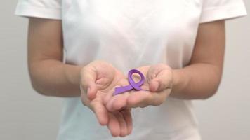 Hand holding purple Ribbon for Pancreatic, Esophageal, Testicular cancer, world Alzheimer, epilepsy, lupus, Sarcoidosis, Fibromyalgia and domestic violence Awareness month. World cancer day concept video