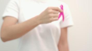 mês de conscientização do câncer de mama em outubro rosa, mão de mulher segura fita rosa para apoiar a vida e a doença das pessoas. mês nacional dos sobreviventes do câncer, mãe e dia mundial do câncer video