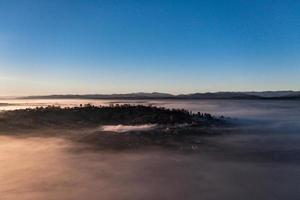 Photo from a drone over the village when the fog fell with thick clouds, a beautiful morning over the village.