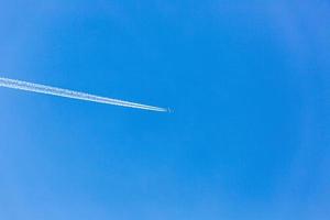 Two engined airplane during flight in high altitude with condensation trails photo