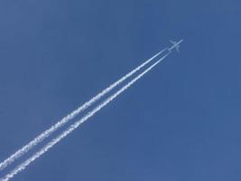 Airplane with condensation trail in blue sky photo