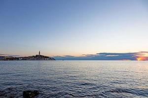 vista al centro histórico de rovinj durante la puesta de sol con reflejos de agua y bonitas formaciones de nubes foto