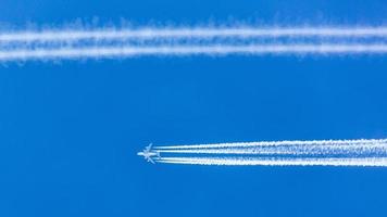 Four engined airplane during flight in high altitude with condensation trails photo