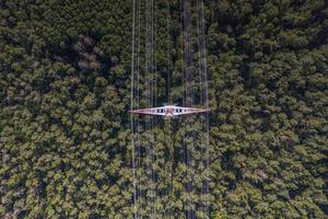 Vertical view on a metal power pole with high voltage wires over forest trees photo