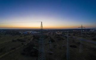Panoramic image of power pylons against spectacular sunset red at dusk with cloudless sky photo