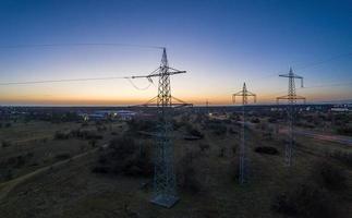Panoramic image of power pylons against spectacular sunset red at dusk with cloudless sky