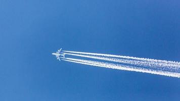 Four engined airplane during flight in high altitude with condensation trails photo