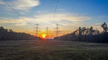 Power poles photographed backlit at sunset in rural area photo