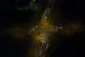 Vertical drone shot of a lighted street intersection at night with traffic photo