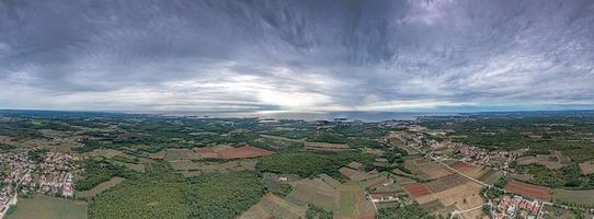 panorama de drones sobre la costa adriática de istria cerca de porec tomado desde gran altura durante el día con cielo nublado e impresionantes rayos de sol foto