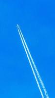 Two engined airplane during flight in high altitude with condensation trails photo